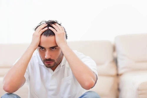 мужчина с бредовым расстройством держится за голову