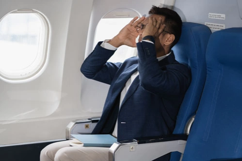Бизнесмен с аэрофобией сидит в самолете и держится за голову