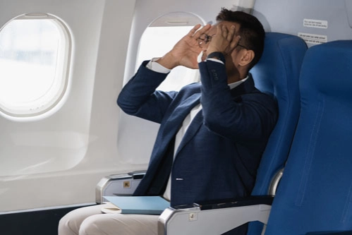 Бизнесмен с аэрофобией сидит в самолете и держится за голову
