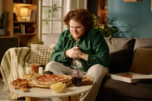мужчина с булимией сидит за столом с едой