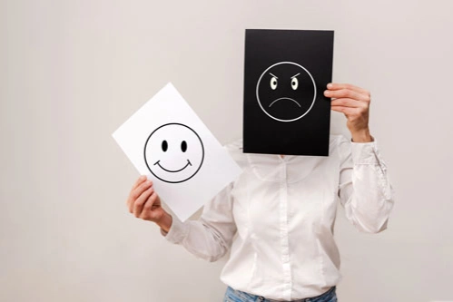 Женщина держит листы бумаги с веселым и депрессивным смайликом