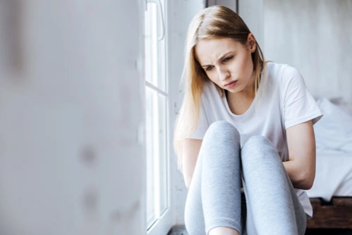 Грустная женщина со стокгольмским синдромом сидит на подоконнике