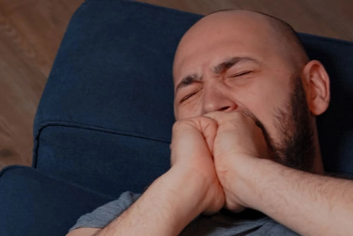 Мужчина с реактивным психозом плачет на диване