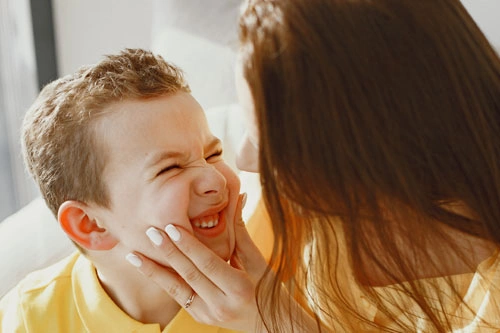 мама держит сына и смотрит есть ли у него во рту волосы