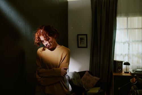 Грустная женщина со стокгольмским синдромом стоит у стены в комнате