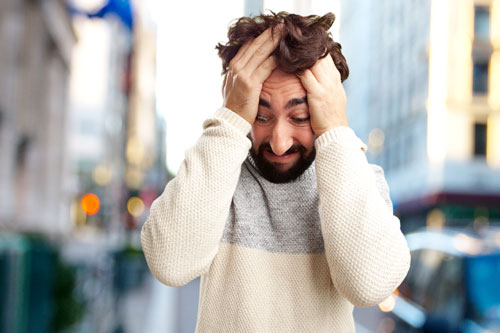Мужчина с агорафобией на улице держится за голову